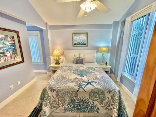 a bedroom with a bed and two lamps and windows at Somehow, Someday, Somewhere, Seaside in St. George Island
