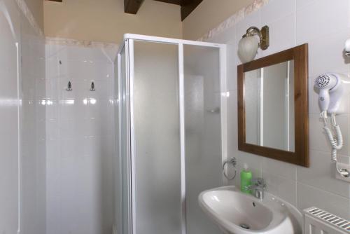 a bathroom with a shower and a sink and a mirror at Aurora Panzió in Bük