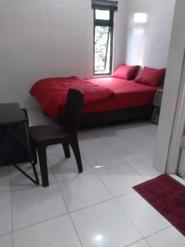 a bedroom with a red bed and a chair at Mgd kos syariah Sentul in Citaringgul 1