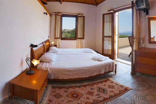 a bedroom with a large bed and a table and window at Lela Kaptani Eftalou Olive Grove in Mithymna