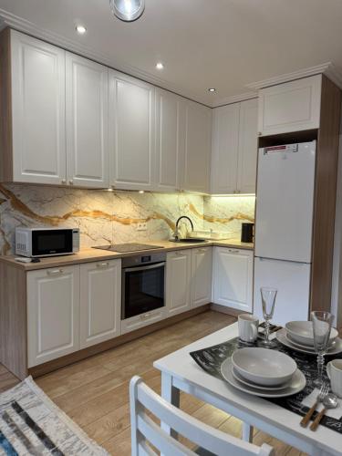 Una cocina con gabinetes blancos y una mesa con platos. en Сердце Арбата, en Almaty
