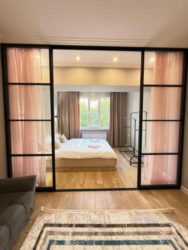 Un dormitorio con una cama y una gran ventana de cristal. en Сердце Арбата, en Almaty