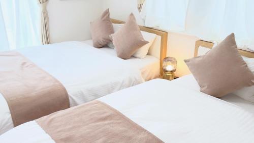 two beds with pillows on them in a room at Villa Seika -盛夏- in Nago