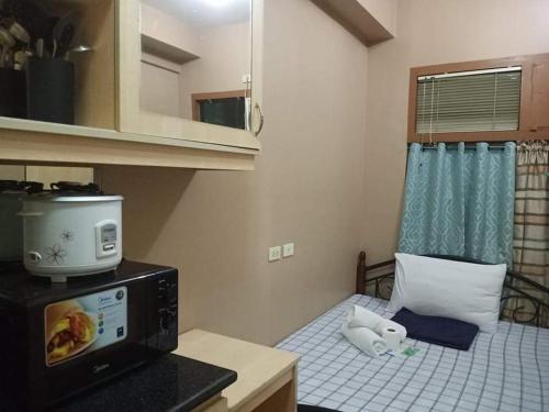 a small room with a bed with a microwave at Budget Condotel in Manila