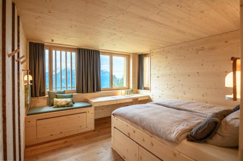 a bedroom with a bed and a desk and windows at Berglodge37 in Altdorf