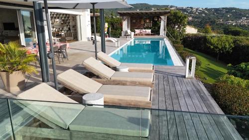 une piscine avec des chaises longues et un parasol dans l'établissement Giulia, villa exceptionnelle, vue mer et Ajaccio, à Porticcio