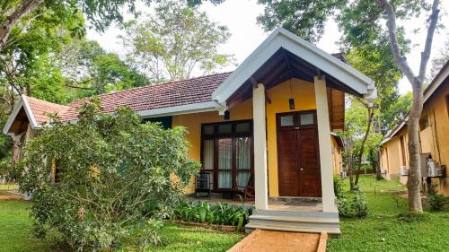 a small yellow house with a brown door at Hotel Kamrel Sigiriya in Sigiriya