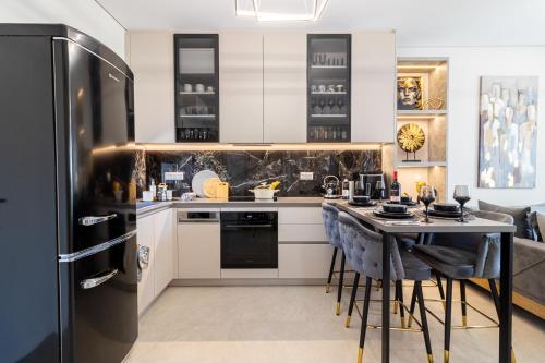 a kitchen with a black refrigerator and a table with stools at Artion Suites Nikiti in Nikiti