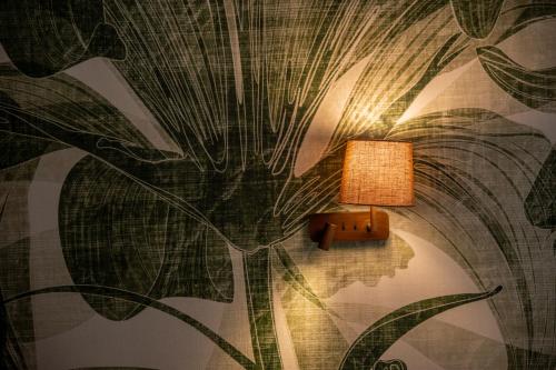 a lamp on a wall with a plant mural at Colle Serrano Relais & SPA in Ripatransone