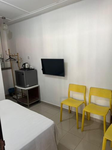 a bedroom with two chairs and a bed and a tv at Nipah Bay Villa in Pangkor