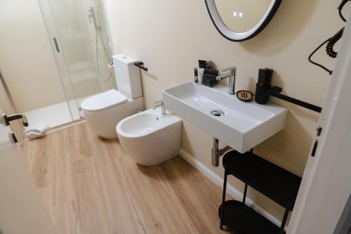 a bathroom with a sink and a toilet and a mirror at xenia apartments & suite in Siracusa