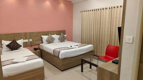 a hotel room with two beds and a red chair at GREEN TERRUS BUSINESS CLASS HOTEL in Chennai