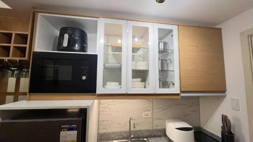 a kitchen with white cabinets and a black microwave at SolAzur Staycation SMDC South Residences Las Piñas with 100MBPS Wifi &NETFLIX &BAR STATION &CITY LIGHTS VIEW in Manila