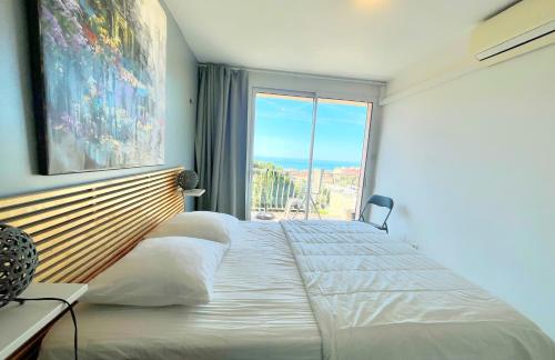 une chambre avec un grand lit avec une grande fenêtre dans l'établissement La Viguerie, à Cassis