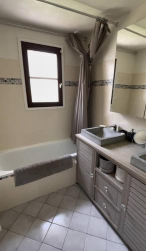 une salle de bain avec une baignoire, un lavabo et un miroir dans l'établissement Maison avec jaccuzi, à Achères-la-Forêt