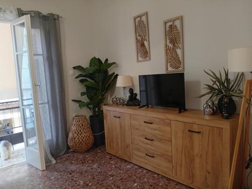 Una sala de estar con un televisor sobre una cómoda de madera. en Chanel Sunshine, en Kalamata