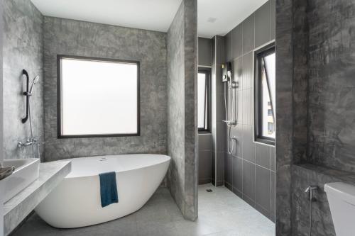 a bathroom with a large white tub and a shower at Kanna Pool Villa in Chiang Mai