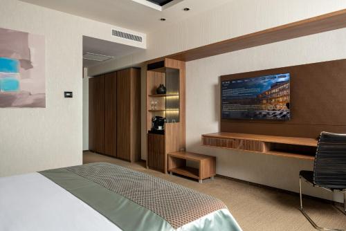 a bedroom with a bed and a flat screen tv at Sky Blue Hotel & Spa in Ploieşti