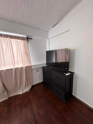 a room with a television and a dresser with a window at Departamento mini Huatulco in Santa Cruz Huatulco