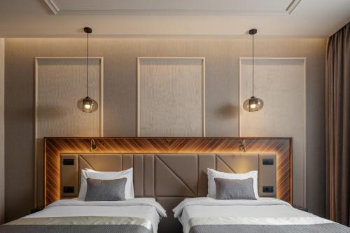 two beds in a hotel room with two lights at Sky Blue Hotel & Spa in Ploieşti