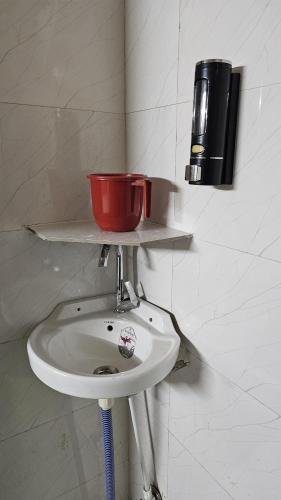 a white sink with a red bowl on top of it at Deva Guest House in Ayodhya
