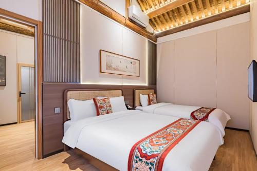two beds in a room with white walls and wooden floors at Beijing city center - Courtyard house hotel located in an ancient Hutong, near the Forbidden City,experience the lifestyle of old Beijing in the exquisite Chinese-style courtyard in Beijing
