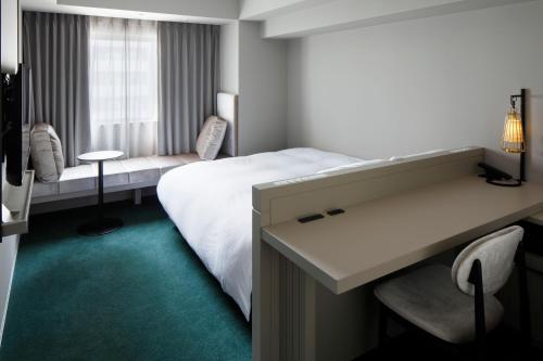 a hotel room with a bed and a desk at HOTEL TORIFITO KANAZAWA in Kanazawa