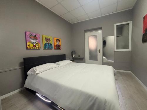 a bedroom with a white bed and paintings on the wall at Casa Rita-Superior Room in Giarre