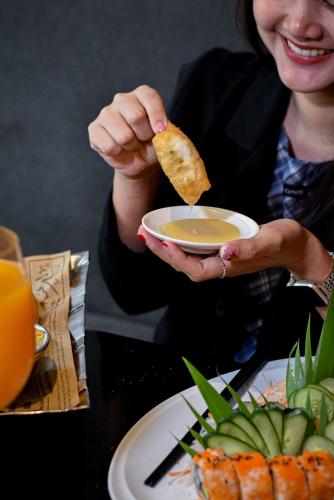 a woman holding a bowl of soup and a piece of food at Holiday Inn Bangkok Sukhumvit by IHG in Bangkok