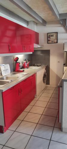 une cuisine avec des armoires rouges et un évier dans l'établissement Gite Rouge à la mer climatisation dans toutes les pièces, à Port-la-Nouvelle