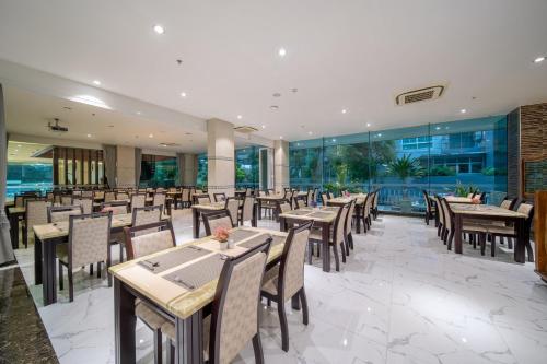 a restaurant with wooden tables and chairs and windows at Royal Prince Resort Pattaya in Pattaya South
