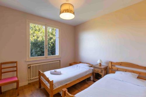 une chambre avec deux lits et une chaise et une fenêtre dans l'établissement Cabana & Villa Le Perthuis Parking, Garden, à Charnay-lès-Mâcon