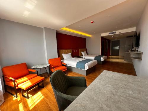 a hotel room with two beds and a couch and chairs at Bojon Hotel Ulaanbaatar - Soyolj Mall in Ulaanbaatar