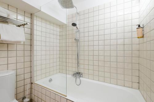 a white tiled bathroom with a tub and a shower at Grimaldi in Cagnes-sur-Mer