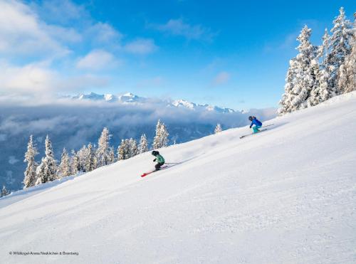 two people are skiing down a snow covered slope at AlpenPura - Chalet mit Sauna und Panoramablick in Neukirchen am Großvenediger