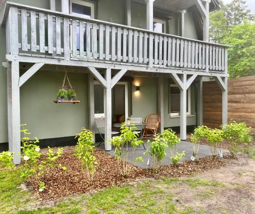 a house with a porch with a deck and a table at Wiesenau Apartments by Restaurant WIESENAU in Prerow