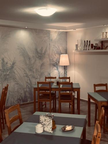 a dining room with tables and chairs and a painting on the wall at Świat Jezior in Mikołajki
