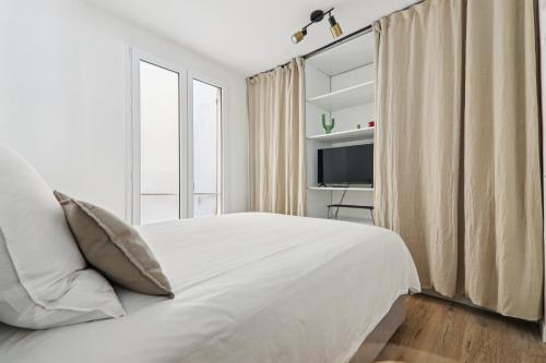 une chambre blanche avec un lit et une télévision dans l'établissement Apartment in Paris 2ème, à Paris