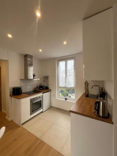 une cuisine avec un évier et une cuisinière four supérieur dans l'établissement Charmant T2 à Puteaux, à Puteaux