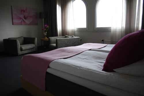 a bedroom with a bed and two chairs and a window at Kumla Hotel in Kumla