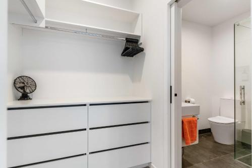 a bathroom with white cabinets and a glass door at Central Beach Pad - Waihi Beach Holiday Home in Waihi Beach
