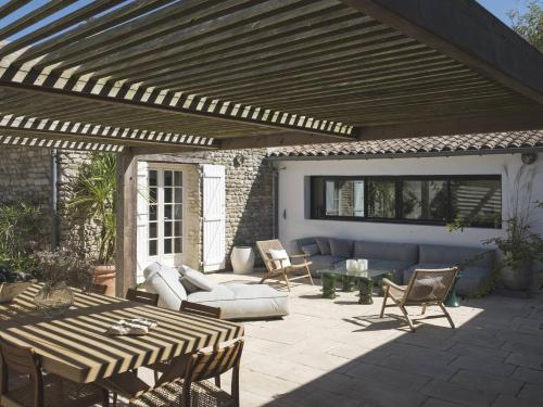 a patio with a wooden pergola and a table and chairs at Maison de famille en pierre in La Couarde-sur-Mer