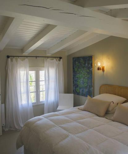 une chambre avec un grand lit blanc avec une fenêtre dans l'établissement Maison de famille en pierre, à La Couarde-sur-Mer