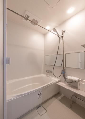 a white bathroom with a tub and a shower at Jasmin T18 高松港近く 静かで美しい別荘 in Takamatsu
