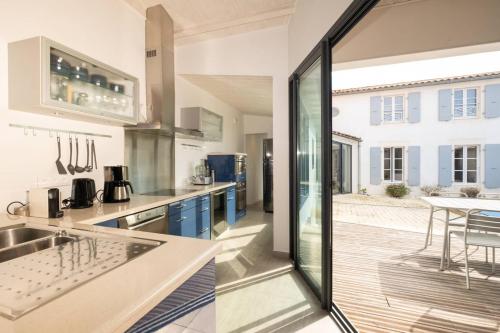 une cuisine avec une porte en verre menant à une terrasse dans l'établissement Maison familiale avec piscine – À 100m du port de La Flotte, à La Flotte