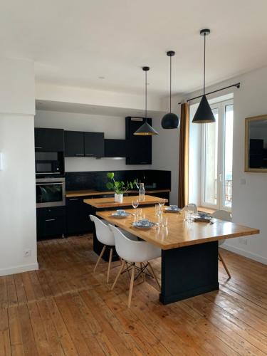 une cuisine avec une grande table et des chaises en bois dans l'établissement Appartement ville mer, à Brest