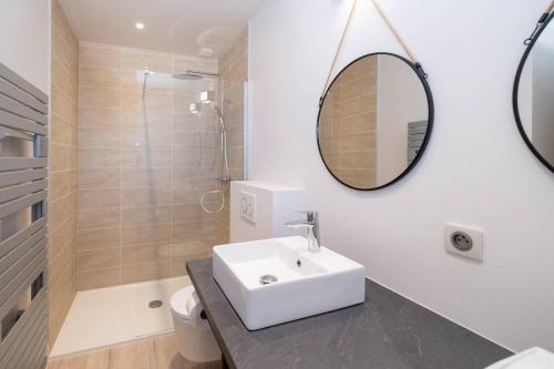 une salle de bain blanche avec un lavabo et un miroir dans l'établissement Les Iles sous le vent - Maison pour les grandes tribus, à Saint-Martin-de-Ré