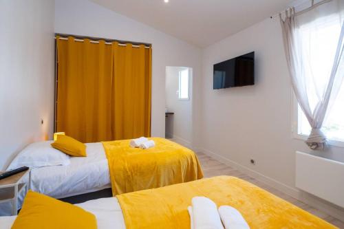 deux lits dans une chambre avec des rideaux jaunes et une télévision dans l'établissement Les Iles sous le vent - Maison pour les grandes tribus, à Saint-Martin-de-Ré