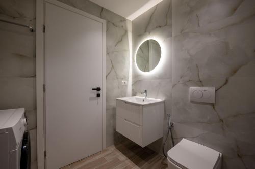 a white bathroom with a sink and a mirror at Regal Luxury Apartments in Sarandë