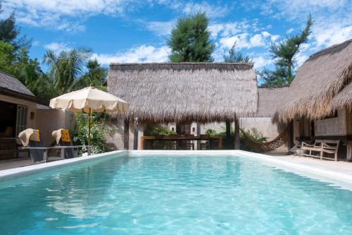 a swimming pool in front of a villa at The Island Houses Gili Meno in Gili Meno